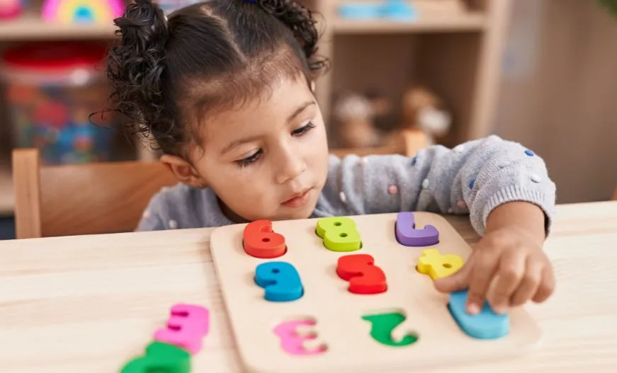 Image is showing the Right Age for Lkg in India with a kid playing with number board